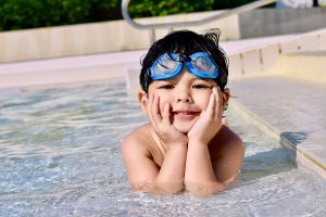 boy with goggles swimming in pool